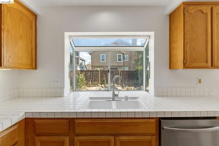 Kitchen with wood finish cabinetry, dishwasher, and tile counters