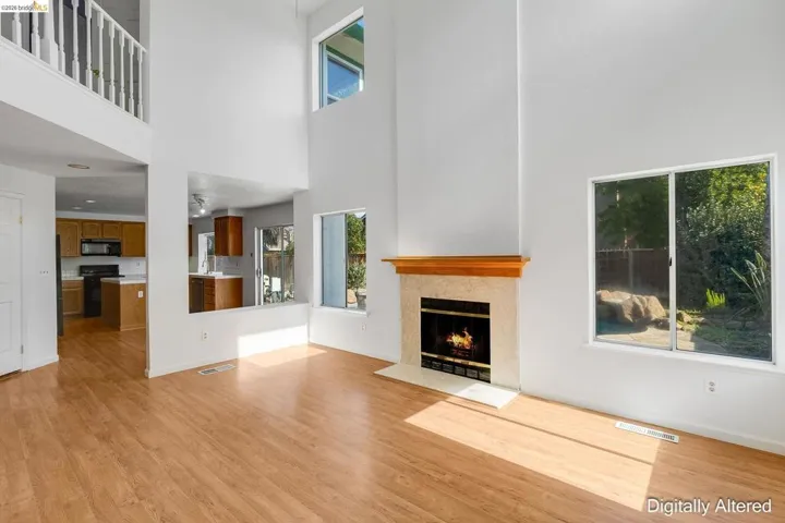Unfurnished living room featuring a high ceiling, light wood-style floors, a warm lit fireplace, and healthy amount of natural light