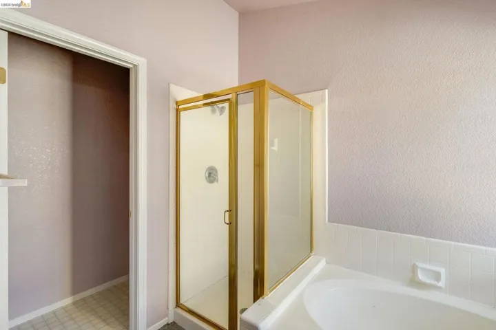 Bathroom with a stall shower, a garden tub, tile patterned floors, and a textured wall