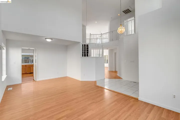 Unfurnished living room with light wood finished floors, a high ceiling, and healthy amount of natural light