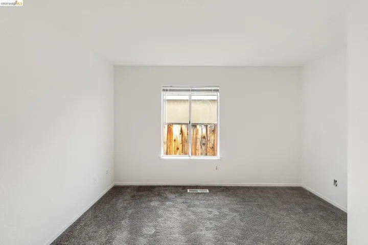 Spare room featuring dark colored carpet and baseboards