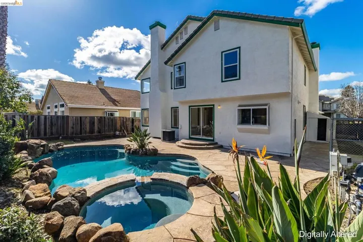 Rear view of house featuring a pool with connected hot tub, a fenced backyard, a patio area, stucco siding, and a chimney
