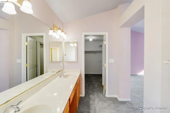 Full bath featuring dark carpet, a spacious closet, double vanity, a chandelier, and lofted ceiling