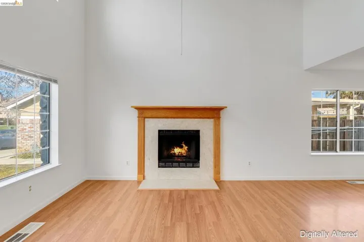 Unfurnished living room with a high ceiling, wood finished floors, and a high end fireplace