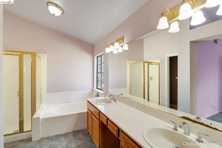 Full bathroom featuring a stall shower, a garden tub, double vanity, light carpet, and lofted ceiling