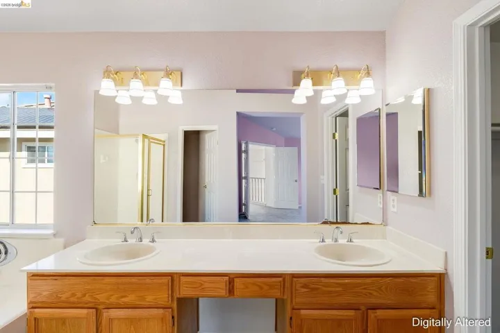 Bathroom with double vanity, a shower stall, and plenty of natural light