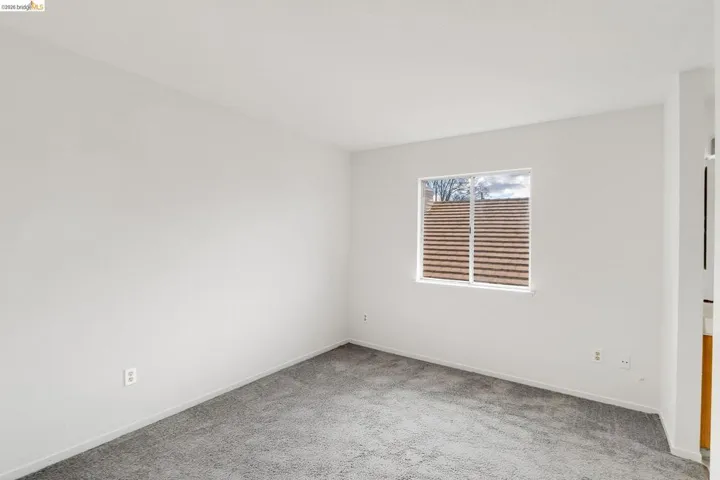 Empty room with light colored carpet and baseboards