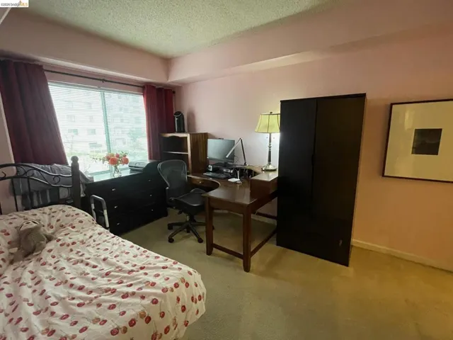 Carpeted bedroom featuring a textured ceiling and an office area