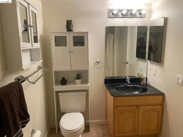 Full bath featuring a shower with curtain, vanity, and a textured wall
