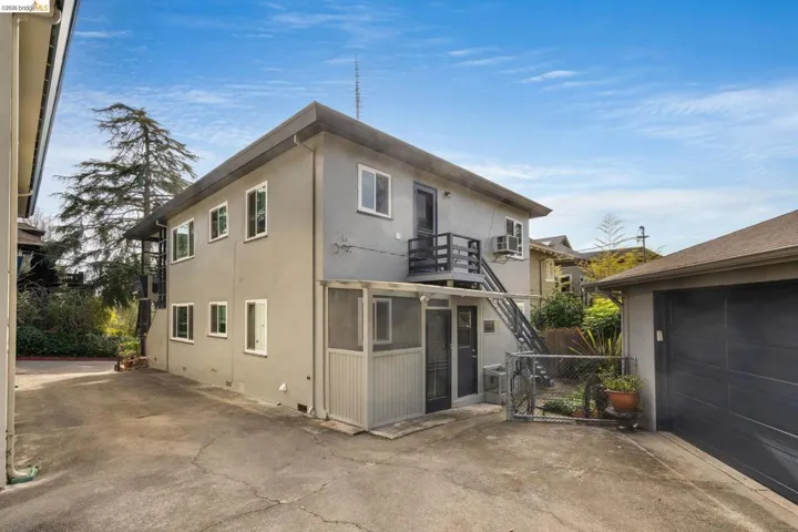View of side of home featuring stucco siding, a balcony, a sunroom, and a garage