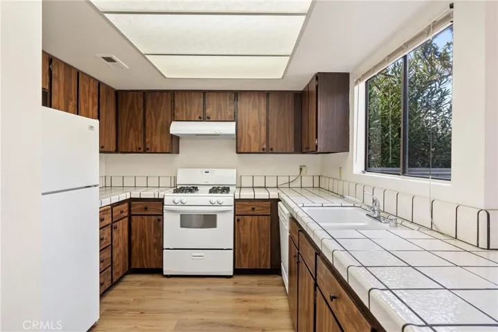 The well-appointed kitchen has laminate wood floors and wrap around cabinets.