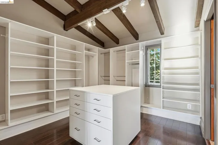 Walk in closet featuring vaulted ceiling with beams and dark wood-style floors