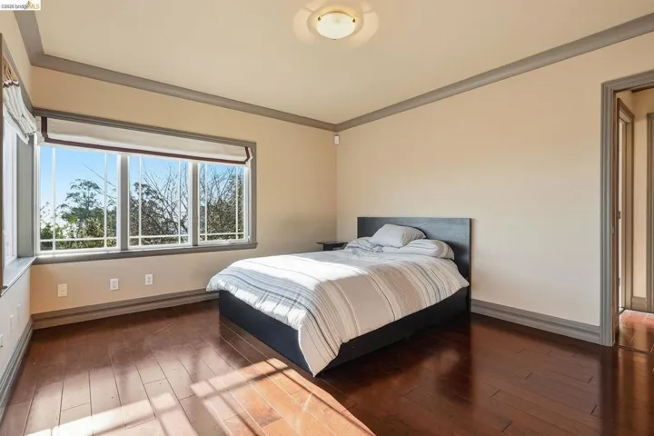 Bedroom with wood-type flooring and crown molding