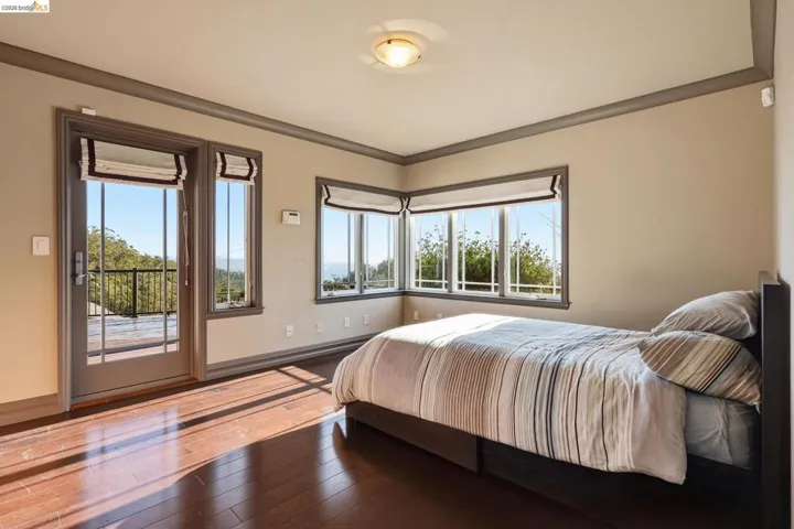 Bedroom with hardwood / wood-style flooring, access to exterior, multiple windows, and crown molding