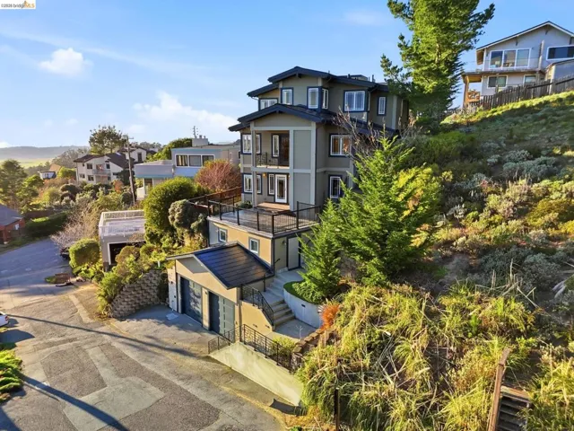 View of front of home with a balcony, stucco siding, a garage, a residential view, and driveway