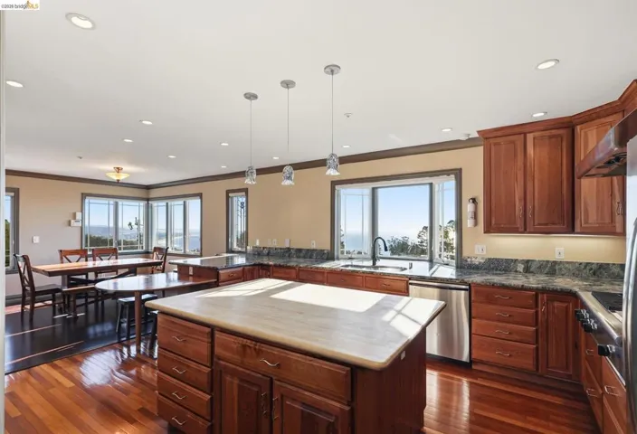 Kitchen with a kitchen island, pendant lighting, dark wood-type flooring, dishwasher, and ornamental molding