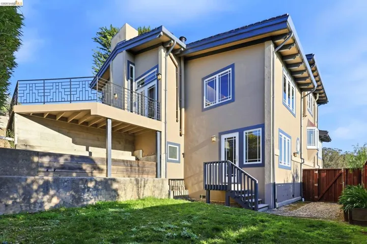 Rear view of house with a gate, stucco siding, and a balcony