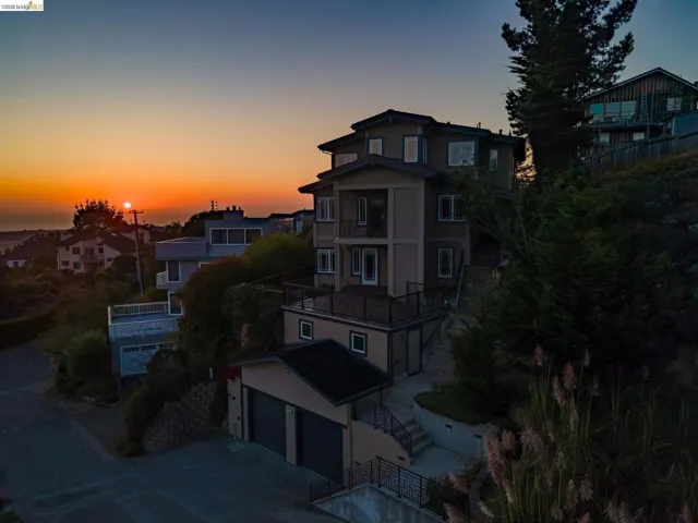 View of front of property featuring a balcony, a residential view, driveway, stucco siding, and an attached garage