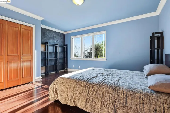 Bedroom featuring dark wood finished floors, ornamental molding, and a closet