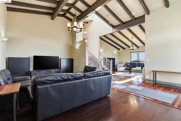 Living room featuring lofted ceiling, hardwood / wood-style flooring, and suspended lighting