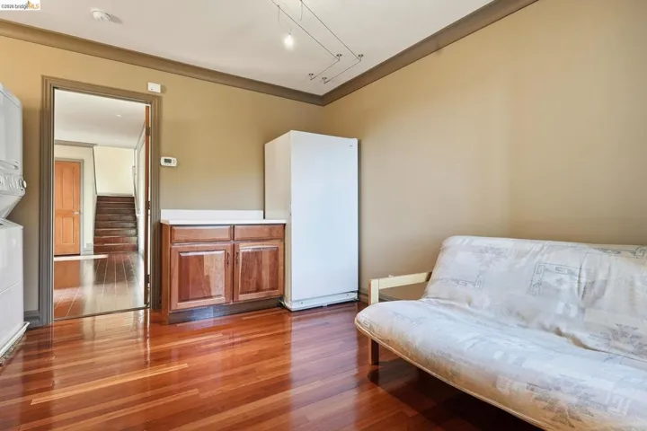 Sitting room with dark wood-type flooring, ornamental molding, and stacked washer / dryer