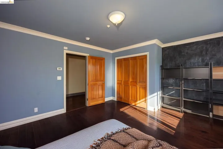 Unfurnished bedroom with dark wood-type flooring, crown molding, and a closet