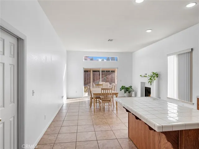 Dining space overlooking backyard with sliding glass doors and cozy fireplace in family room.