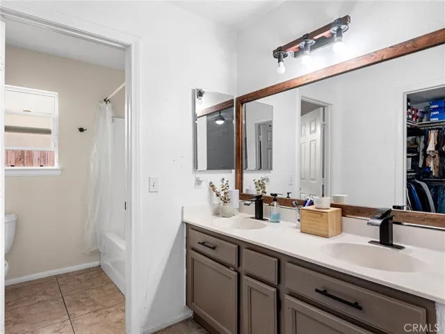 En-suite bathroom with dual sinks, generous vanity space, and a functional layout designed for convenience. Includes a shower/tub combination and ample storage.