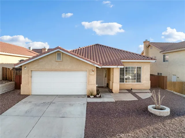 Two-car attached garage with extended driveway and low-maintenance desert landscaping.