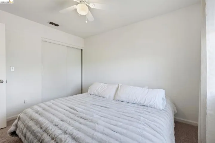 Carpeted bedroom with a closet and a ceiling fan
