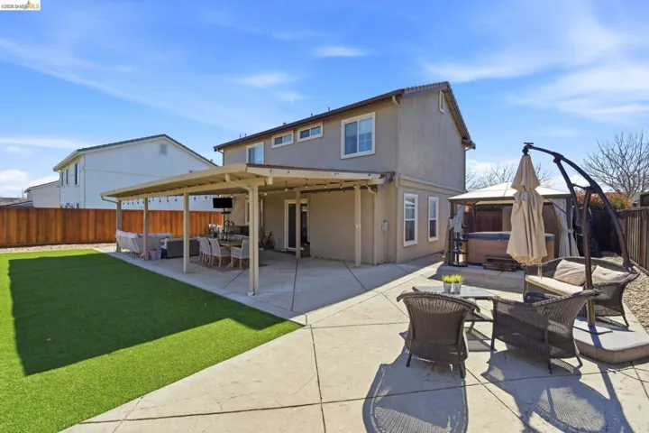 Rear view of property with outdoor furniture, a fenced backyard, a gazebo, a patio area, and a hot tub