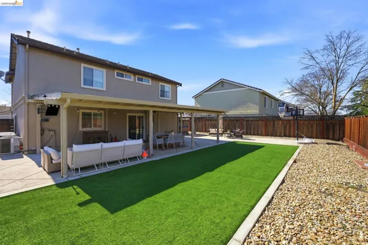 Rear view of property featuring a patio area, stucco siding, a fenced backyard, and outdoor furniture
