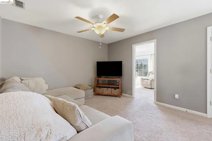 Carpeted living area featuring baseboards and a ceiling fan