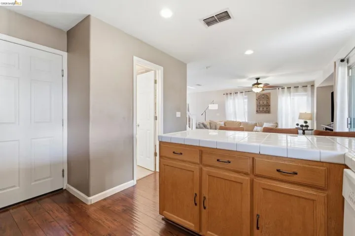 Kitchen with open floor plan, ceiling fan, tile counters, dark wood finished floors, and recessed lighting