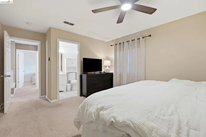 Bedroom featuring light colored carpet, ceiling fan, and ensuite bathroom