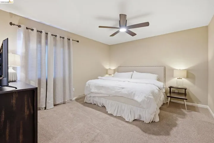 Bedroom with light carpet and a ceiling fan
