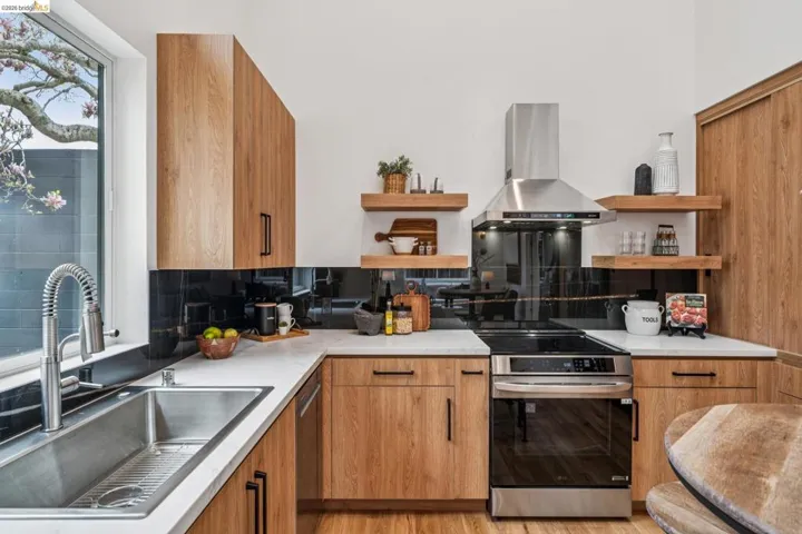Kitchen with open shelves, wood finish cabinetry, stainless steel appliances, and island range hood