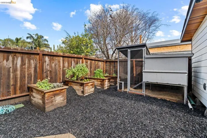 fenced backyard featuring exterior structure, a vegetable garden, and an outbuilding