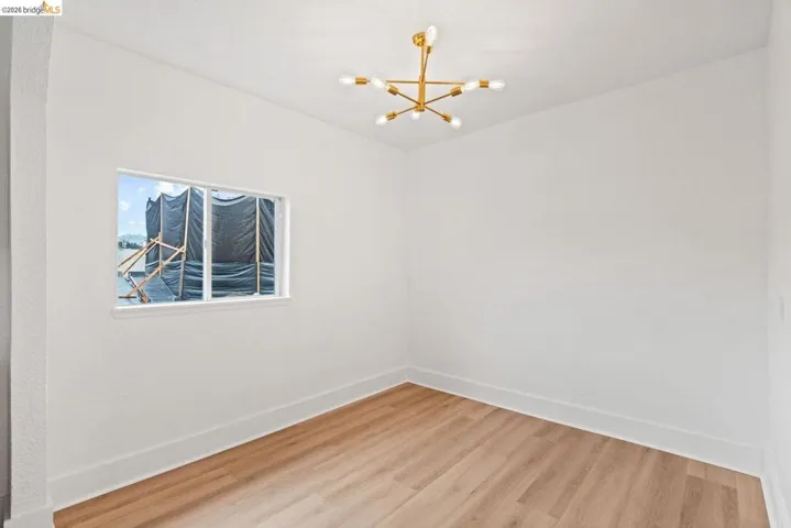 spare room with wood finished floors and a chandelier