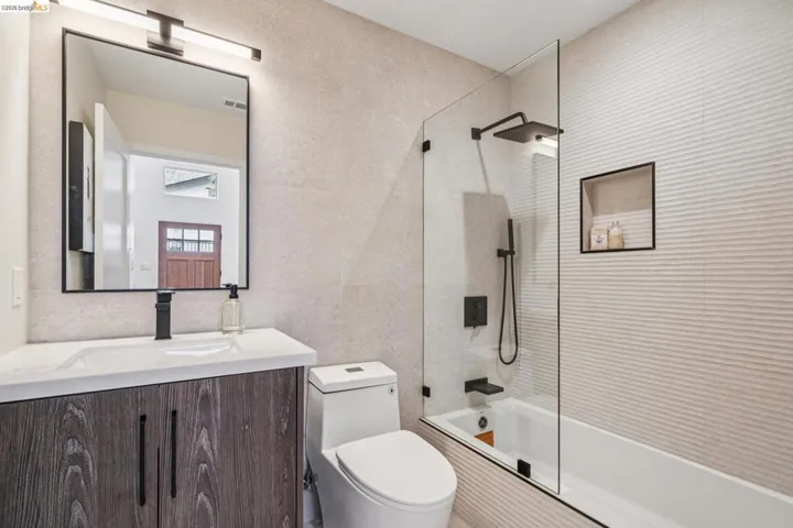 Bathroom with bathing tub / shower combination, vanity, and tile walls