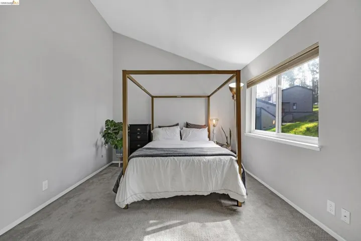 Carpeted bedroom with vaulted ceiling and baseboards