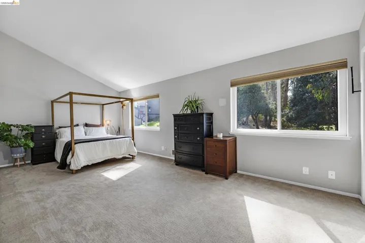 Carpeted bedroom with baseboards and lofted ceiling