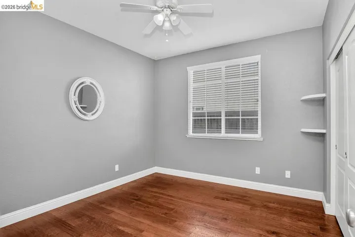 Empty room with dark wood finished floors and a ceiling fan