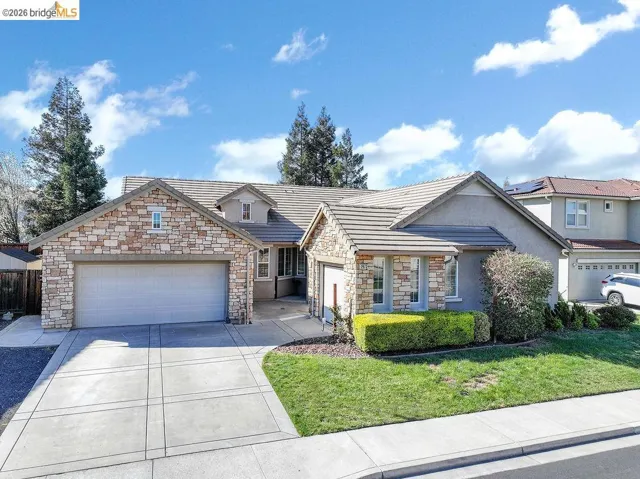 View of front of home featuring a tile roof, an attached garage, stone siding, stucco siding, and concrete driveway
