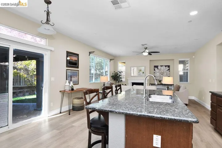 Kitchen with a center island with sink, a breakfast bar area, light wood-style flooring, and dark stone countertops