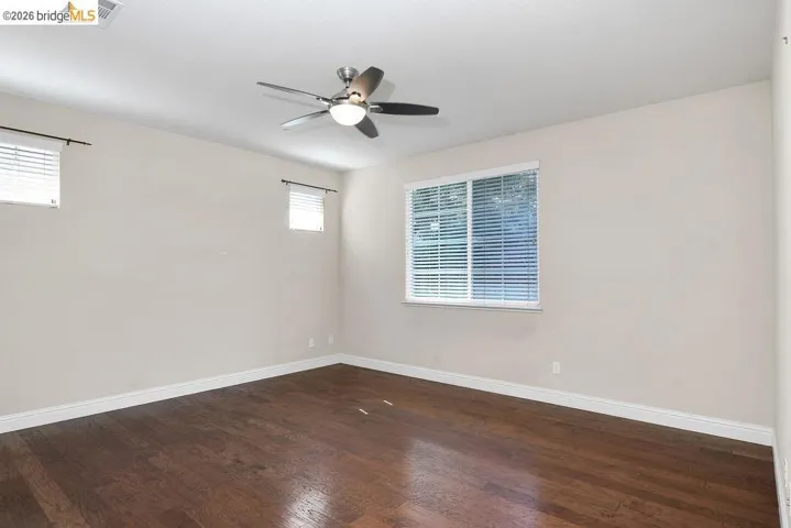 Empty room featuring dark wood-style floors and ceiling fan