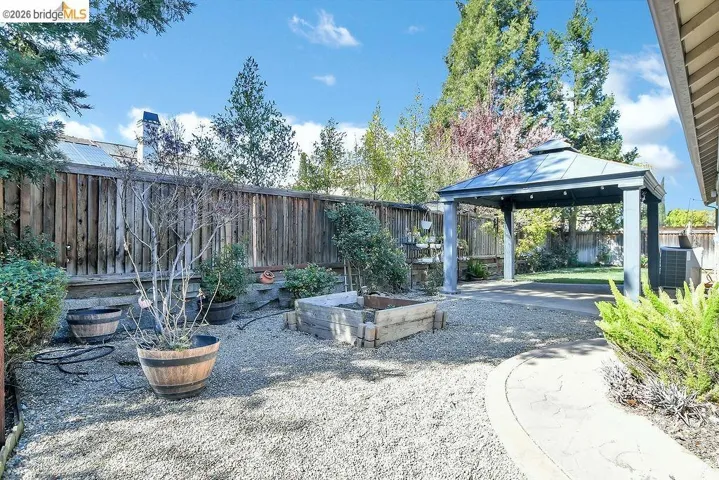 Fenced backyard with a patio area, a vegetable garden, and a gazebo