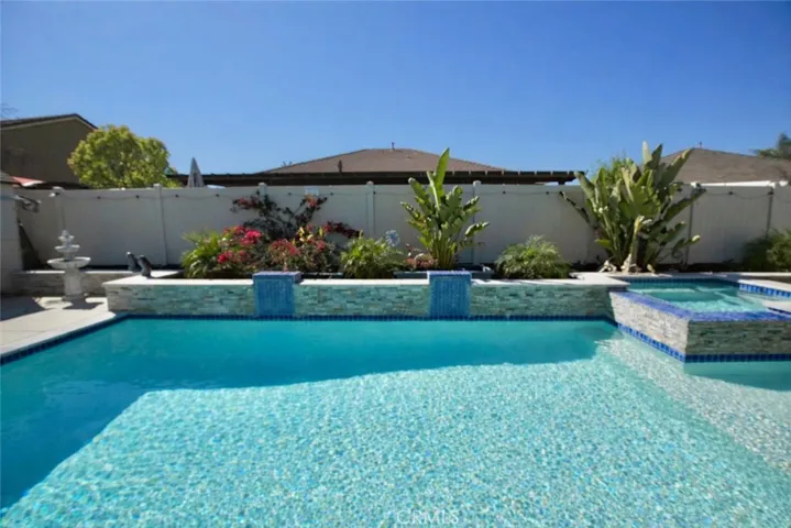 Sparkling pool with 2 waterfall columns, spa with overflow stacked stone spillway landing on safe beach shelf area perfect for lounge chairs or kiddie area