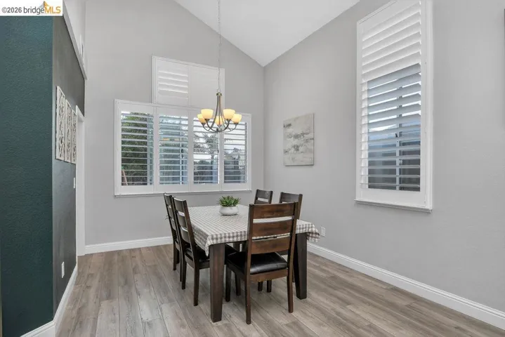 Dining room featuring lofted ceiling, light wood-style floors, a chandelier, and healthy amount of natural light