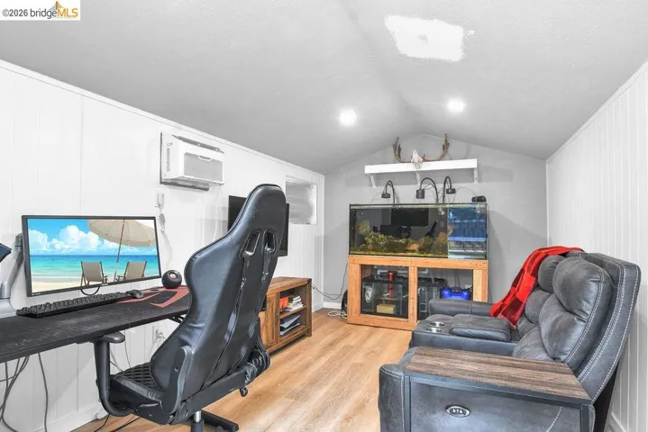 Office space with light wood-style flooring, wood walls, and a textured ceiling